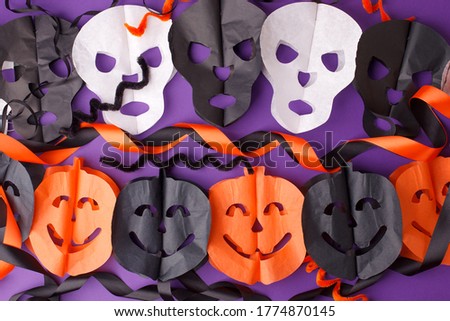 Halloween, holidays and decoration concept - jack-o-lantern pumpkins and skull garland on purple background, traditional autumn october party decor, seasonal holiday, classic color