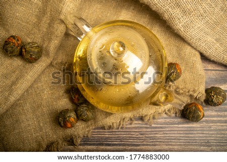 Flower tea brewed in a glass teapot on a background of homespun fabric with a rough texture. Close up.