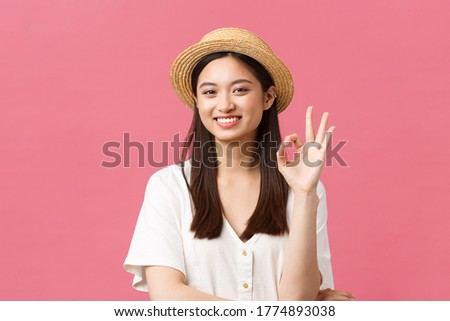 Beauty, people emotions and summer leisure and vacation concept. Happy cute asian girl in straw hat showing okay sign and smiling happy, recommend product or store, give advice, approve awesome place