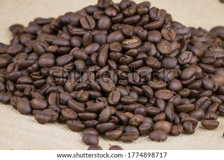 Many coffee beans Place it on a brown fabric surface. The picture is partially clear.