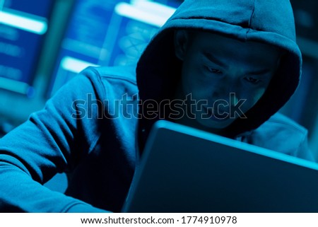 Closeup of asian male hacker use laptop to commit a crime