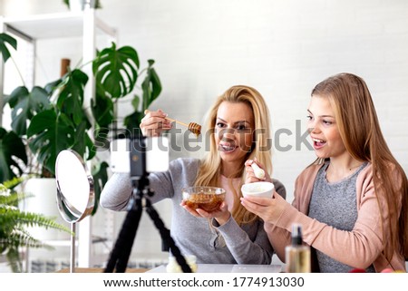Mother and her daughter record video about natural cosmetics with hand made cream and honey