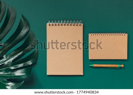 Notepads made of crafted paper with a pen on green background with monstera leaf. Love and romance theme. Eco friendly materials concept.