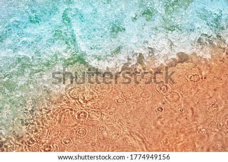 Sea wave on the sand beach, soft focus. Summer background. Waves with splashes and foam.