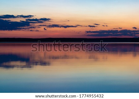Natural background. Evening sky and its reflection in calm water after sunset. Blurred defocused photo 
