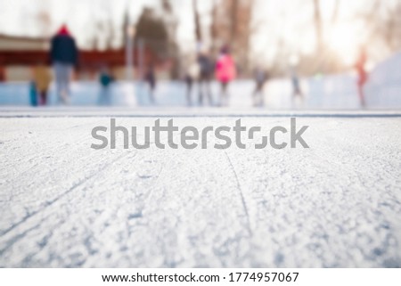 WHITE WINTER BACKGROUND WITH BLUR OF PEOPLE AND SCRATCHED ICE FIELD AT OUTDOOR ICE HOCKEY STADIUM, CITY LIFE AT COLD WINTRY  DAY DURING FROSTY WEATHER, LIFESTYLE DESIGN