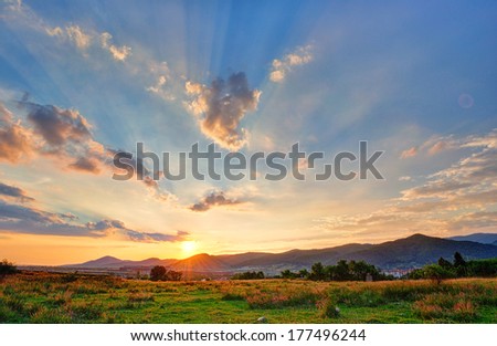 Colorful autumn sunset with sun rays coloring the clouds