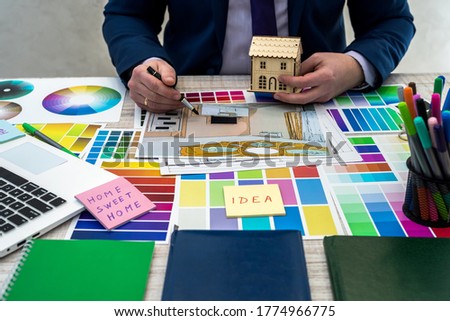 Interior designer's hand working with illustration sketch, color scheme of material, notebook and material. Concept of home renovation, repair  or decoration 