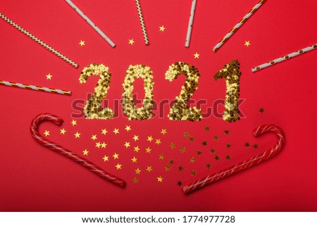 Gold stars sparkle in the shape of the number 2021 on a red background. New Year festive concept. Flat lay style.