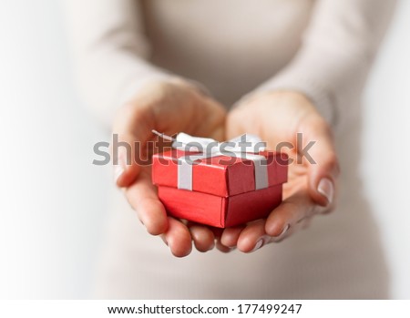 Woman holding small red present box in hands.