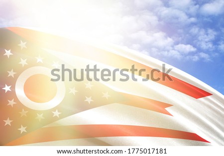 flag of State of Ohio against the blue sky with sun rays