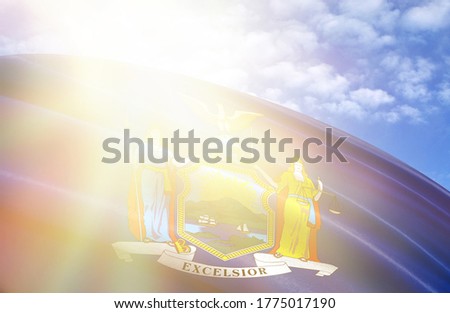 flag of State of New York against the blue sky with sun rays