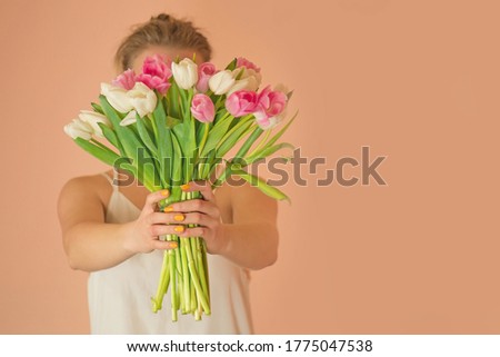 Fashion style photo of pretty girl in white dress with tulips.