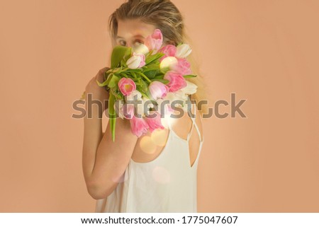 Portrait of happy young girl in casual clothes taking a tulip bouquet.
Fashion style photo of pretty girl in white dress with tulips.

