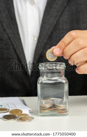Man in suit in office collect money in jar, concept photo