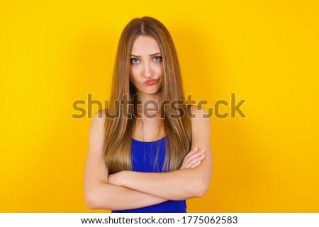 Picture of angry young Caucasian woman crossing arms standing isolated over background. Looking at camera.