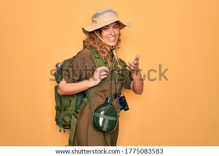 Young blonde explorer woman with blue eyes hiking wearing backpack and water canteen smiling cheerful offering palm hand giving assistance and acceptance. Royalty-Free Stock Photo #1775083583