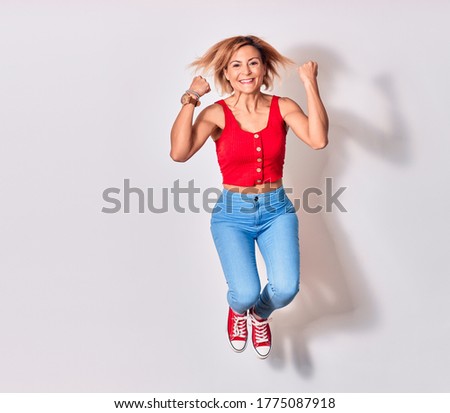 Young beautiful woman wearing casual clothes smiling happy. Jumping with smile on face doing winner gesture with thumbs up over isolated white background