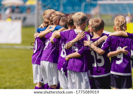 Sporty Boys in a Team on the Field. Group of Children in Purple Shirts Huddling Before the Final Game. Horizontal Picture of Junior Level Boys School Sports Team