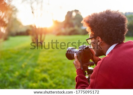 Photographer as a landscape photographer with camera while photographing in nature