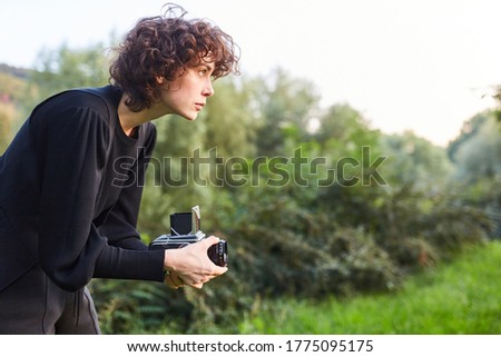 Young woman as a photographer with medium format camera makes landscape photography
