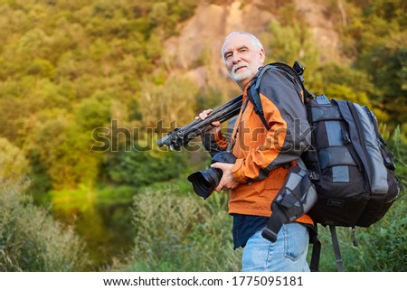 Professional photographer with camera backpack and tripod in nature