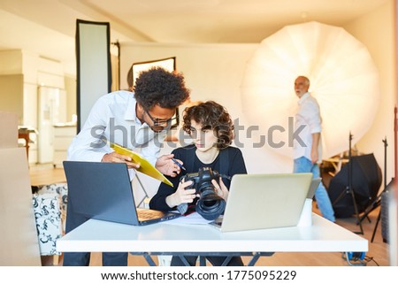 Photo assistant with checklist and photographer on laptop plan photoshoot