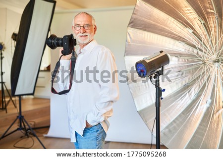 Cool freelance photographer with digital camera in front of a flash unit
