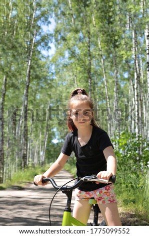 Portrait of a funny girl of eight years with long blond hair on a summer walk in the forest