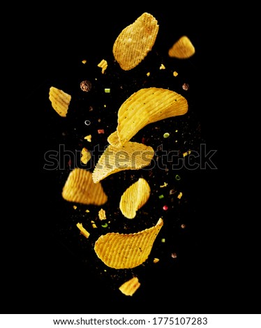 Levitation flying potato chips with onions and peppers on a black background. Advertising concept. Royalty-Free Stock Photo #1775107283