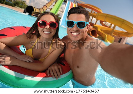 Happy couple taking selfie at water park. Summer vacation