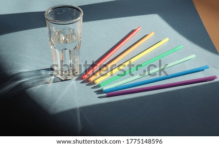 Colorful straws for drinking water with a glass of water on colorful backgrounds in the sun - the concept of daily use of clean water