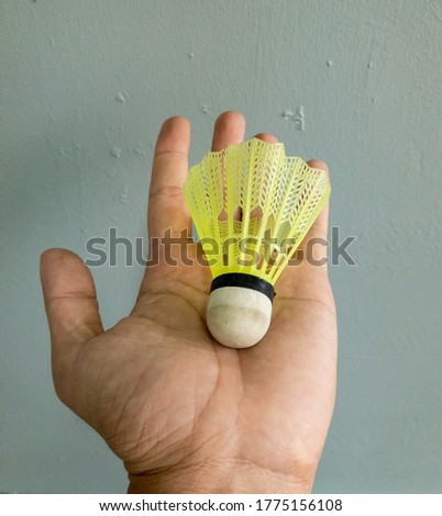 Hand holding a green shuttlecock isolated on a grey background