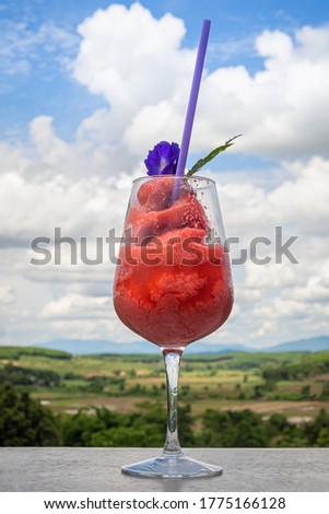 Fresh healthy watermelon smoothie in glass against the background of sky, clouds and mountains. Healthy nutrition and vitamins