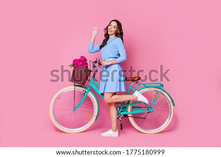 Full length body size profile side view of her she attractive lovely cheerful cheery wavy-haired lady gardener walking bike floristry shop delivery waving hi isolated pink pastel color background