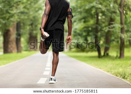 Cropped of black guy exercising at park, stretching legs before running, back view, copy space