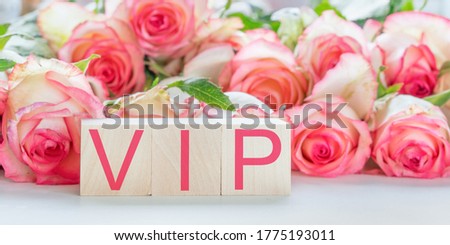 vip sign by red letters on wooden blocks on table rose flowers background hotel service concept