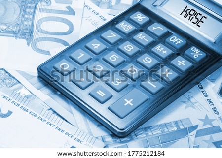 Euro banknotes, calculator and German translation for crisis