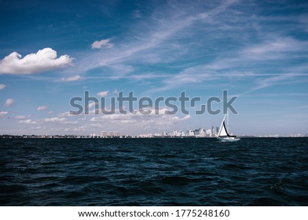 Sail boat in the ocean with the skyline on the background. Skyline view in the summer day. Travel background Miami. Miami cityscape.
