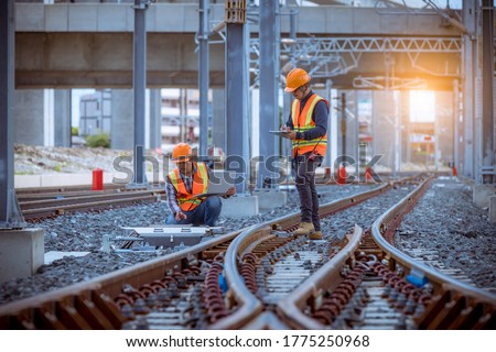 Engineer railway under inspection and checking construction railway switch and checking work on railroad station by laptop.Engineer wearing safety uniform and safety helmet in work. Royalty-Free Stock Photo #1775250968