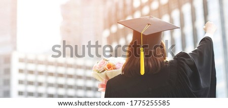 shot back side young female student in hand raising arms over fist thumb up and holding a bouquet of flowers during commencement success graduate of the university, Concept education congratulation. Royalty-Free Stock Photo #1775255585