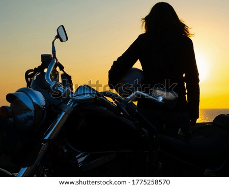 Close up of girl and motorcycle silhouettes by the sea at sunset