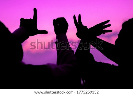 couples hands showing LOVE in silhouette against bluish sky