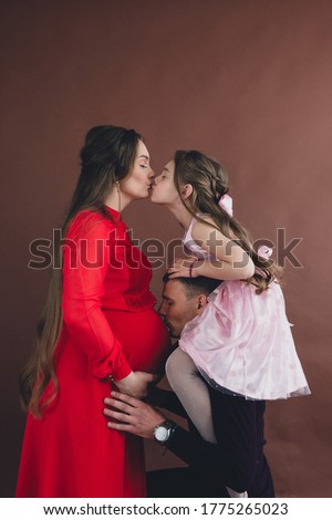 Pregnant woman belly being kissed by husband and daughter