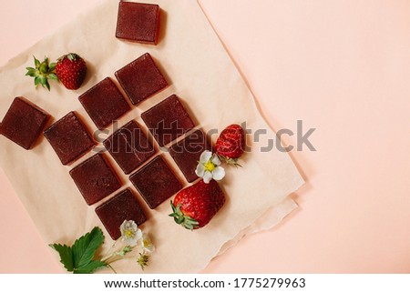 Pieces of strawberry marmalade and strawberry berries on a pink background. Top View. Flat lay