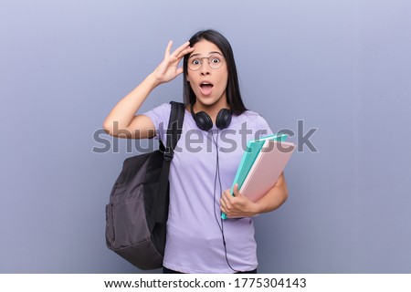 young pretty latin student woman against gray wall