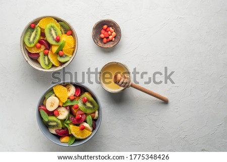 Concept of low calories delicious desserts. Summer fresh bowl with colorful fruit salad. Healthy natural organic food. Tasty sweet snack. Grey background. Top view. Copy space