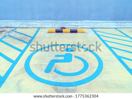 Parking signs for the disabled on the parking lot floor, Disability sign in car park in shopping mall concept, Graphic of a person sitting in a wheelchair symbol on grey ground in parking lots.