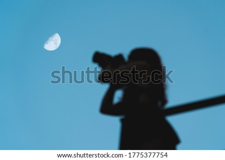 Girl taking picture of the moon in clear blue sky