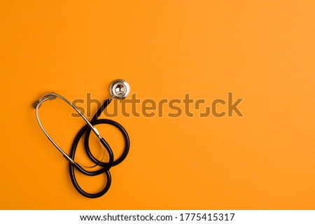 Covid-19 Coronavirus concept. Stethoscope medicine accessory, orange background with copy space. top view